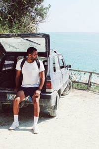 Young man standing by sea against sky