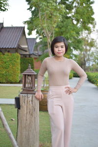 Portrait of smiling young woman standing against trees