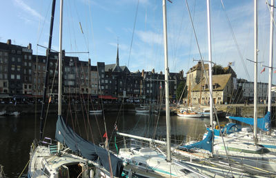 Sailboats moored in harbor against buildings in city