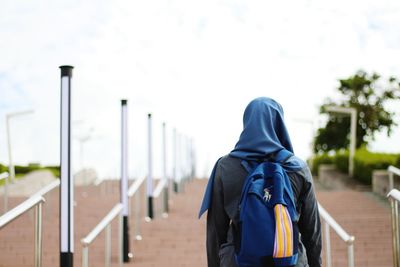 Rear view of a woman standing on railing