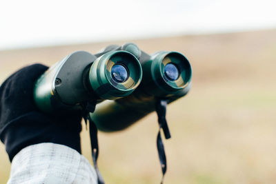 Cropped hand with glove holding binocular