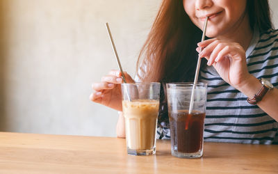 Midsection of woman drinking glass on table