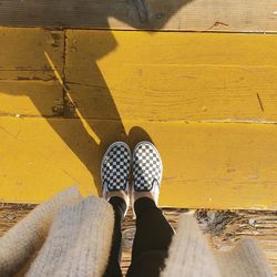 Low section of woman standing on yellow wooden floor