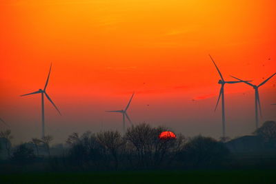 Scenic view of sunset with windmills in background