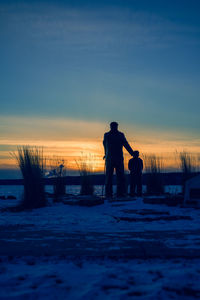 Silhouette men standing on field during sunset