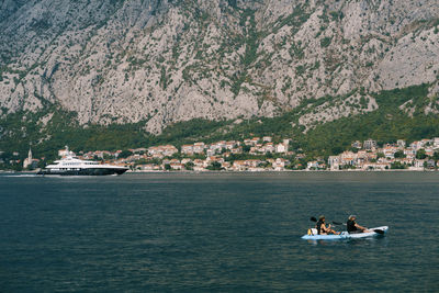 People on sea against mountain