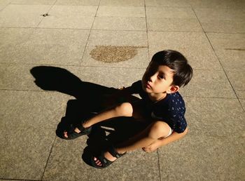 High angle portrait of cute boy sitting on street