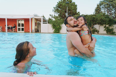Father with two daughters swimming in pool