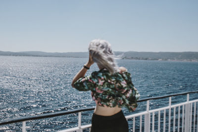 Rear view of woman looking at sea against clear sky