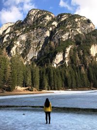 Rear view of woman standing on rock against sky