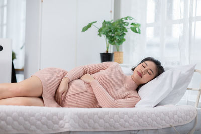 Midsection of woman sleeping on bed