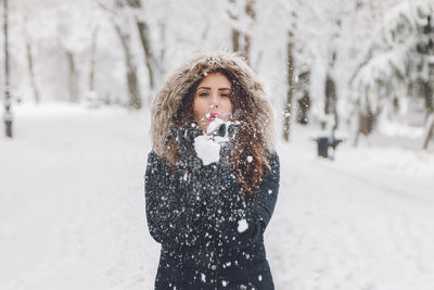 Young woman standing against snow covered tree