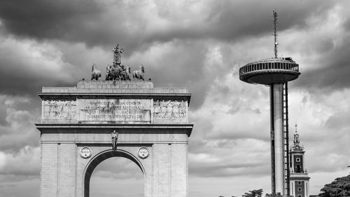 Low angle view of town arch against cloudy sky