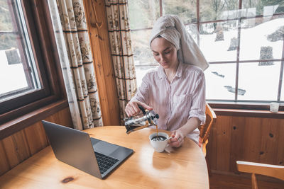 Young woman using phone on table