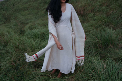 Low section of woman standing on grassy field