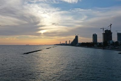 View of sea against buildings during sunset