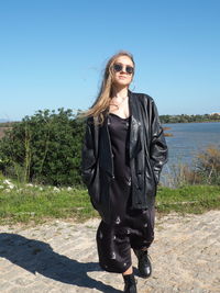 Portrait of smiling young woman wearing sunglasses against sky