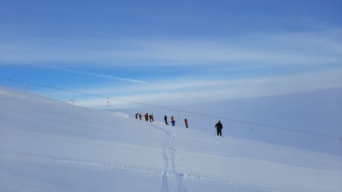 People skiing on snow covered landscape against clear sky