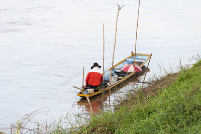Rear view of man sitting on boat at lake