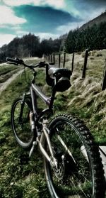 Close-up of bicycle on field against sky