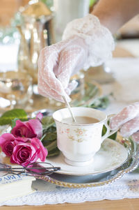 English retro still life and a woman's hand in a white lace glove stirring coffe