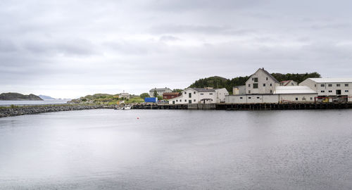 Buildings by lake against sky