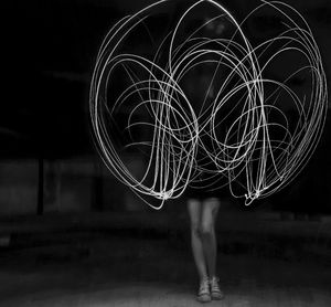 Low section of woman with light painting at night