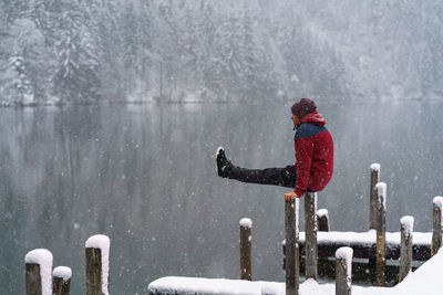 Man on pier over lake against mountains during winter