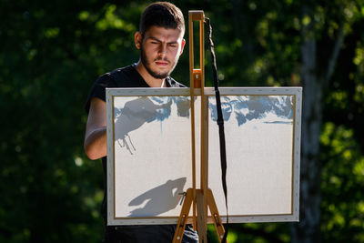 Young artist create drawing while standing against trees