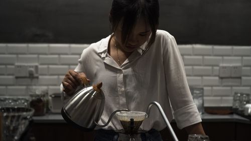 Woman making coffee in kitchen at home