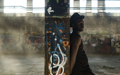 Side view man standing against graffiti wall