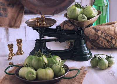 Green tomatoes in weight scale on table