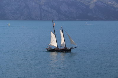 Sailboat sailing on sea against mountain