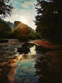 Scenic view of lake by buildings against sky at sunset