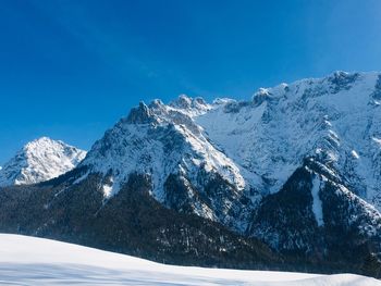 Scenic view of snowcapped mountains against blue sky