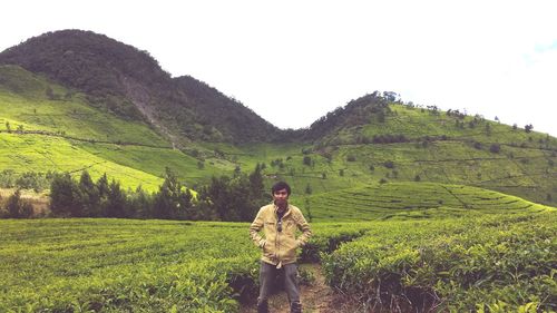 Man on field by mountain against sky