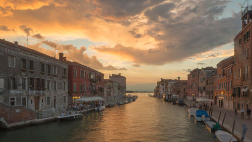 Canal amidst buildings against sky during sunset