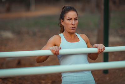 Confident woman exercising on bars in park