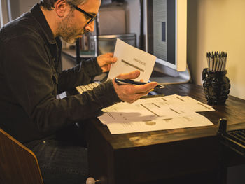 Midsection of man reading book while sitting on table