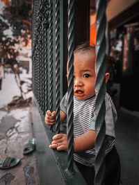Portrait of cute baby boy standing by railing