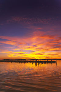 Scenic view of sea against dramatic sky during sunset