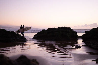 Scenic view of rocks in sea against sky during sunset