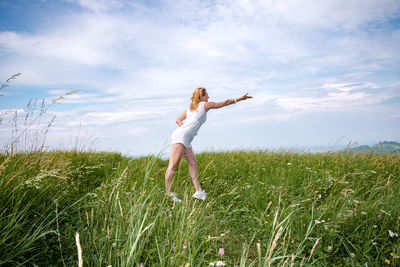 Full length of woman standing on field against sky