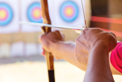 Close-up of man with bow and arrow aiming at target