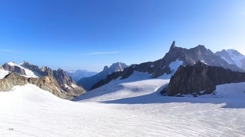 Scenic view of snowcapped mountains against clear blue sky