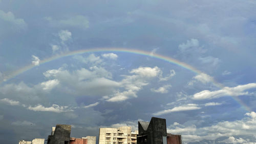 Low angle view of rainbow over buildings against sky