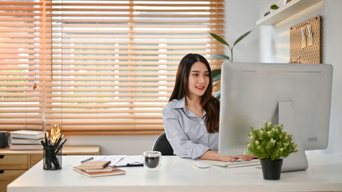 Young woman using mobile phone while sitting on table