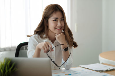 Portrait of young woman using phone on table