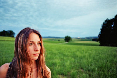 Portrait of beautiful woman on field against sky