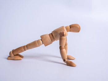 Close-up of figurine on wood against white background